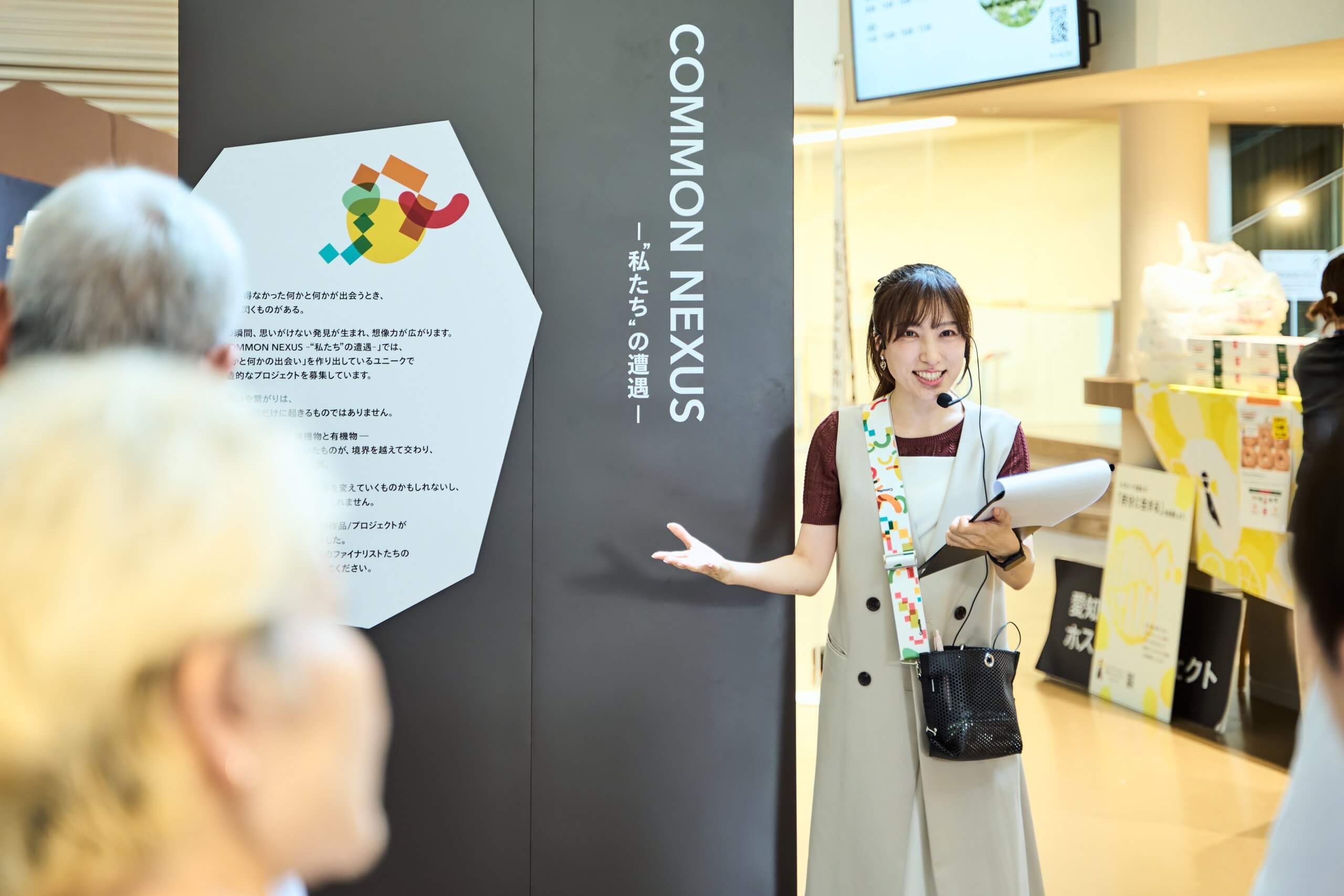 画像：女性スタッフがマイクを持ち、説明をしている様子。