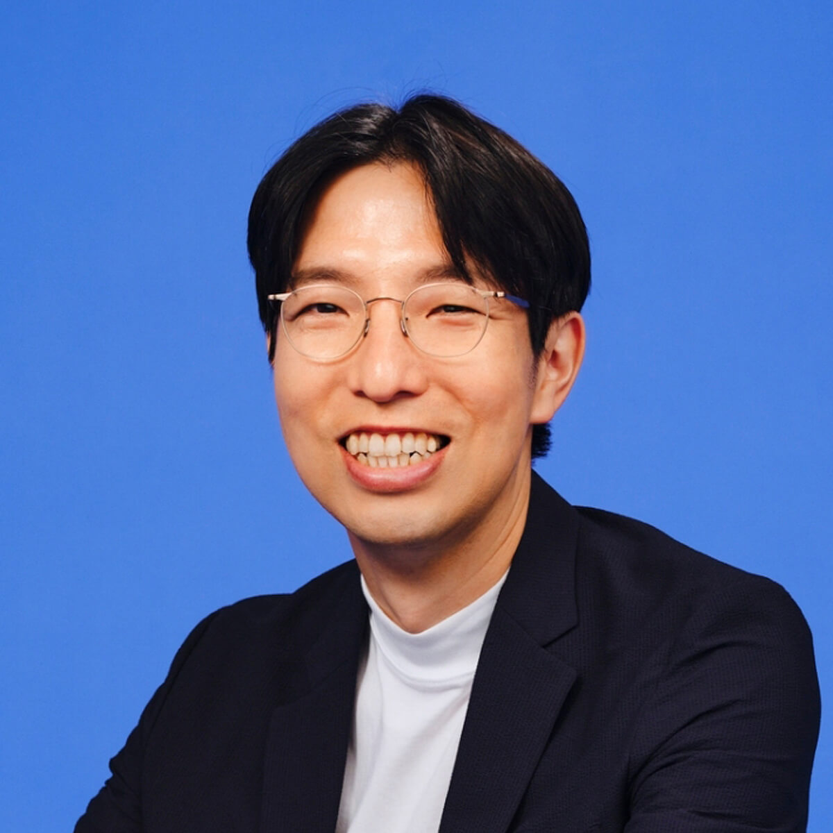 男性の写真。ジャケットを着て笑顔を見せている
