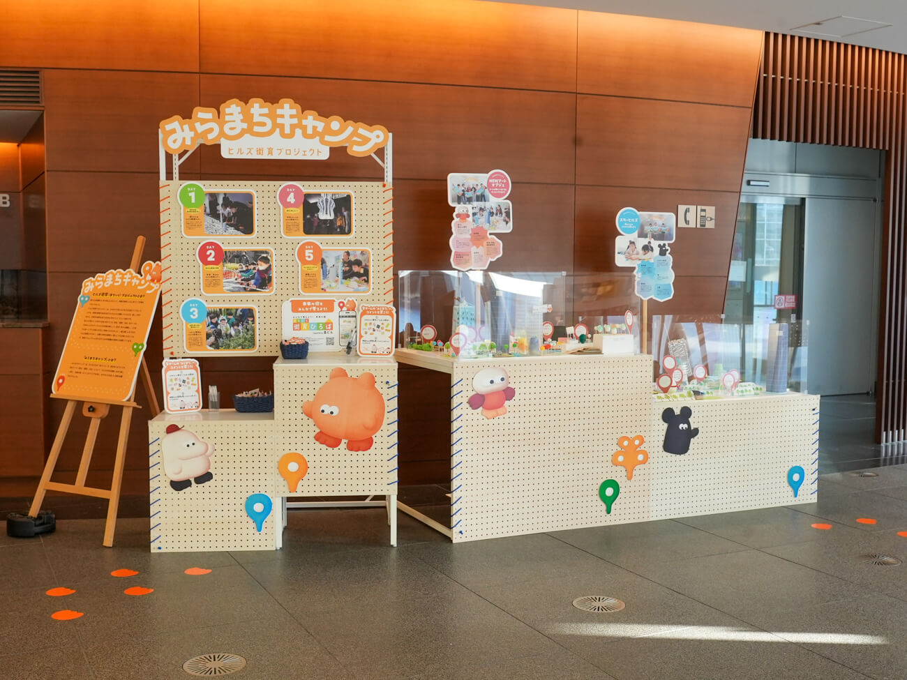 ヒルズで行われた展示の様子。ロビーらしき場所に什器が置かれ、街の模型が並んでいる