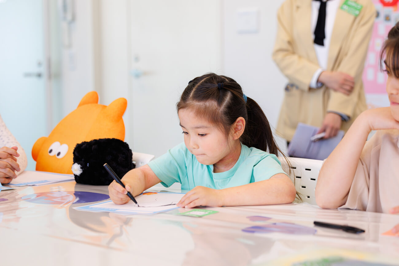 紙に何かを書き込む子どもの写真。真剣そうな表情で机に向かっている