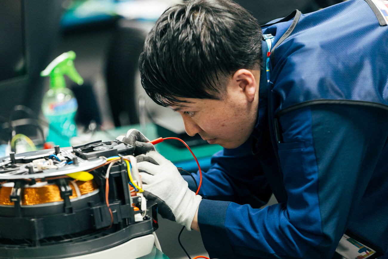 修理技術員が、真剣な眼差しで家電を修理している様子