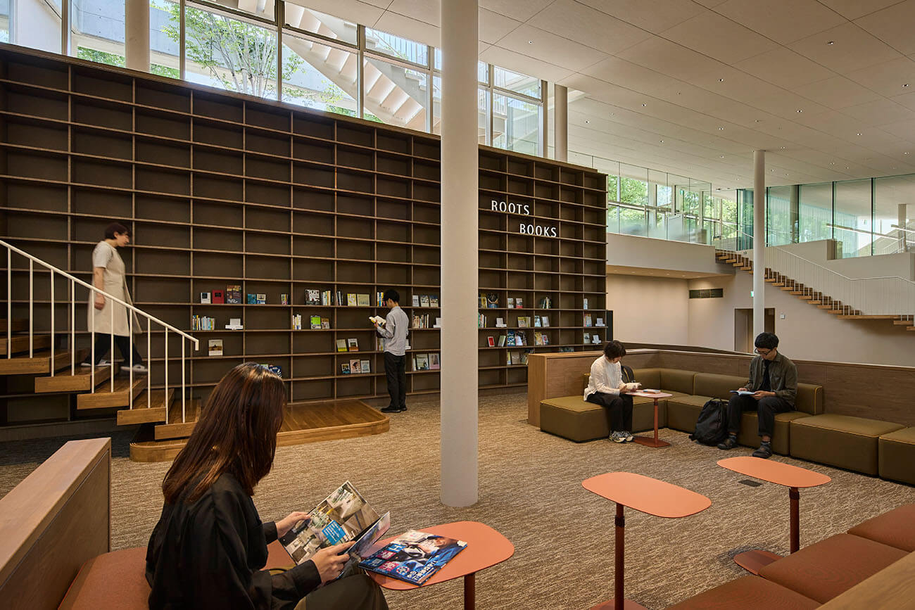 施設内のブックエリア。壁一面の大きな本棚に書籍が並び、来館者が本を手に取ったりソファで読書を楽しんだりしている。