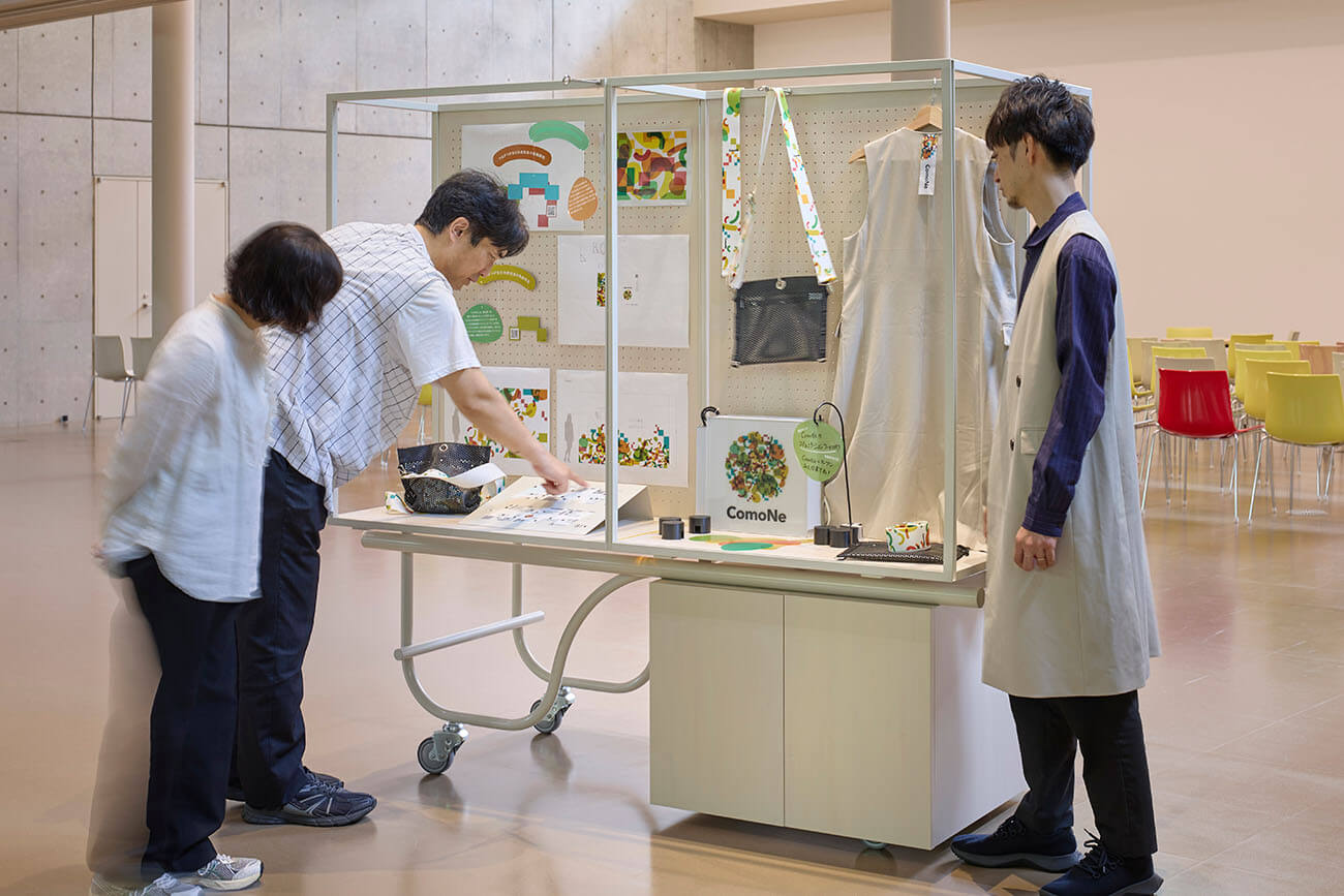Project Materialの展示什器を囲み、資料や制作物を見ながら対話する様子。