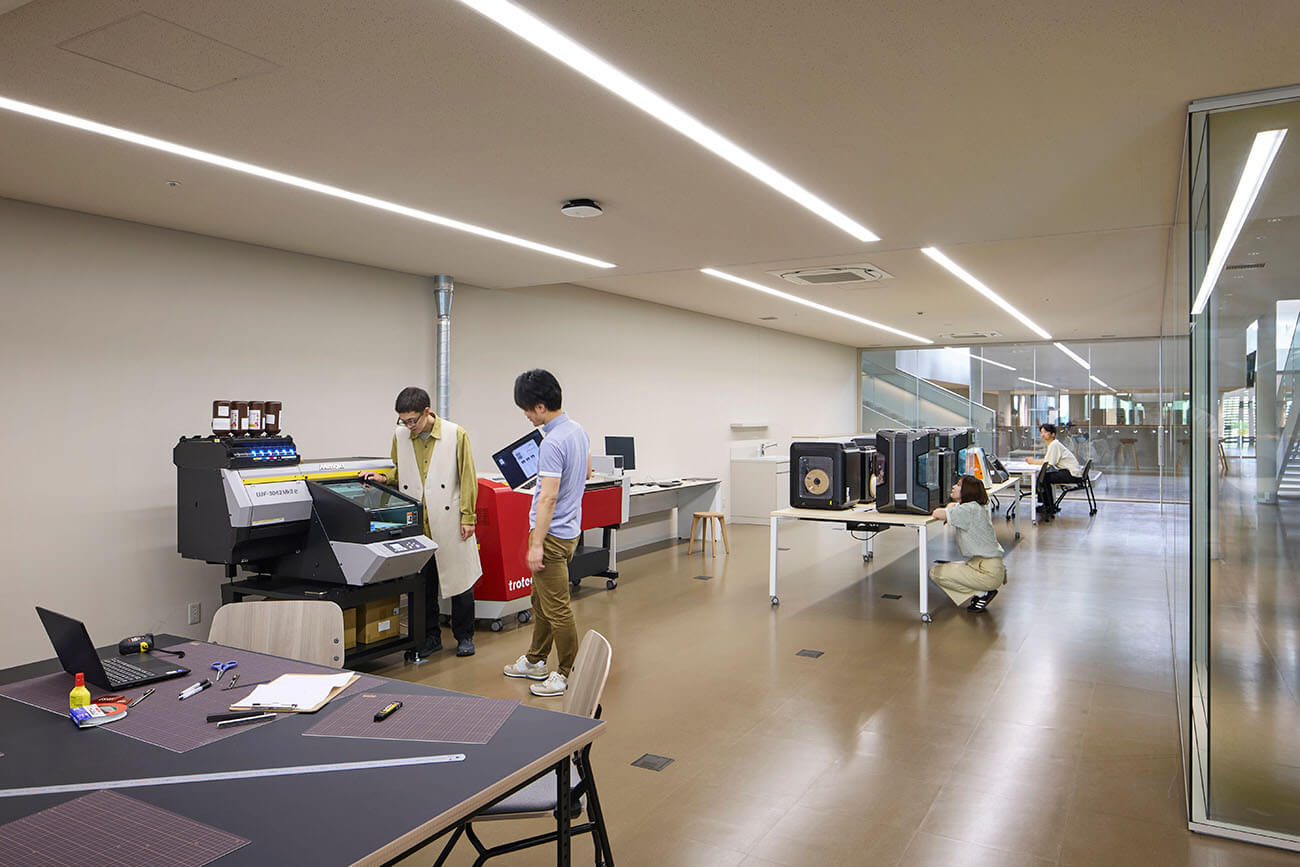 レーザーカッターや3Dプリンターなどの機材が並ぶFabスペース。利用者が機械を操作したり作業を行ったりしており、ものづくりやプロトタイピングに活用できる環境が整っている