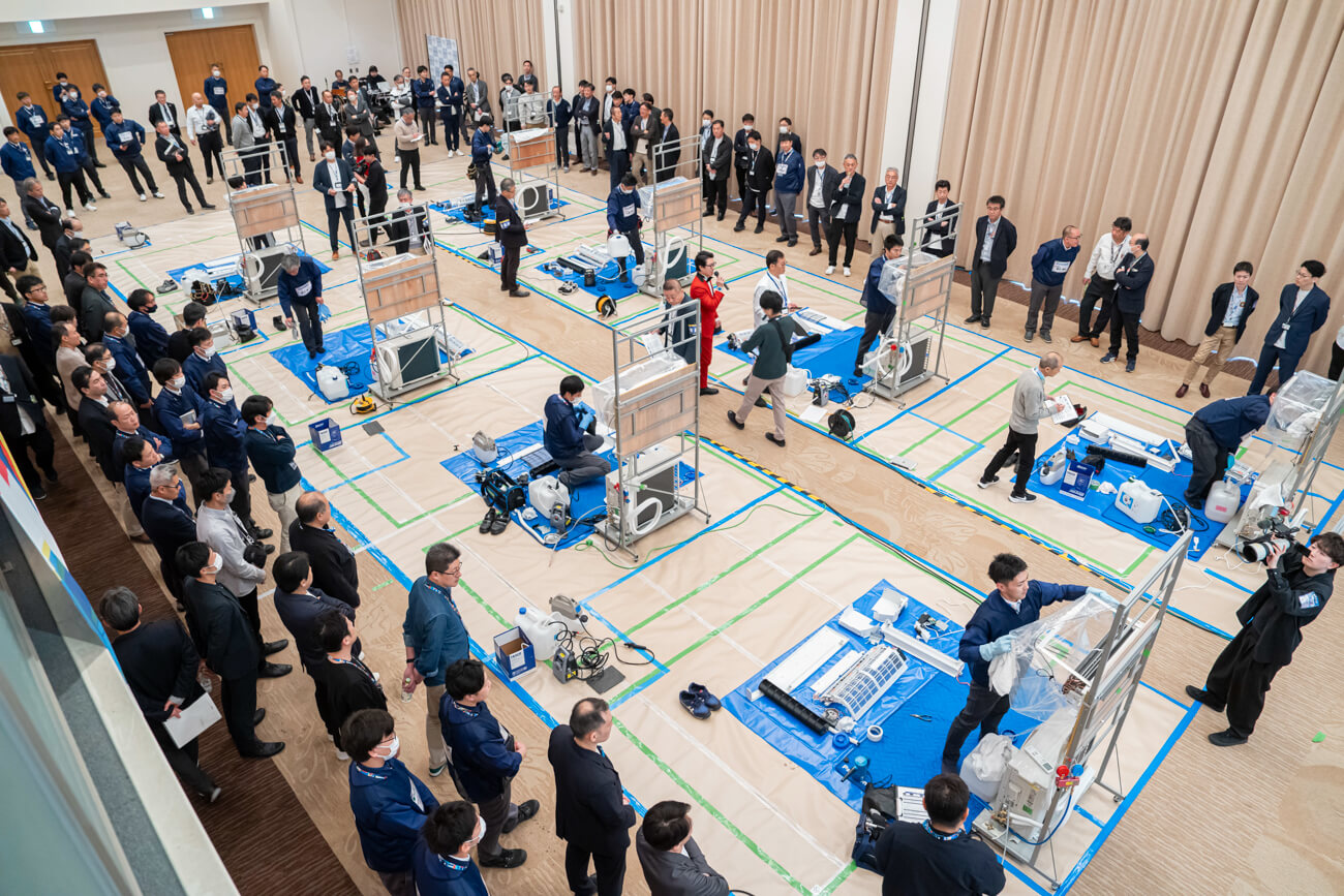 ギノリンピックの会場の様子。俯瞰した目線で撮影された写真には、たくさんの家電とそれを修理する技術員たちの姿が写っている