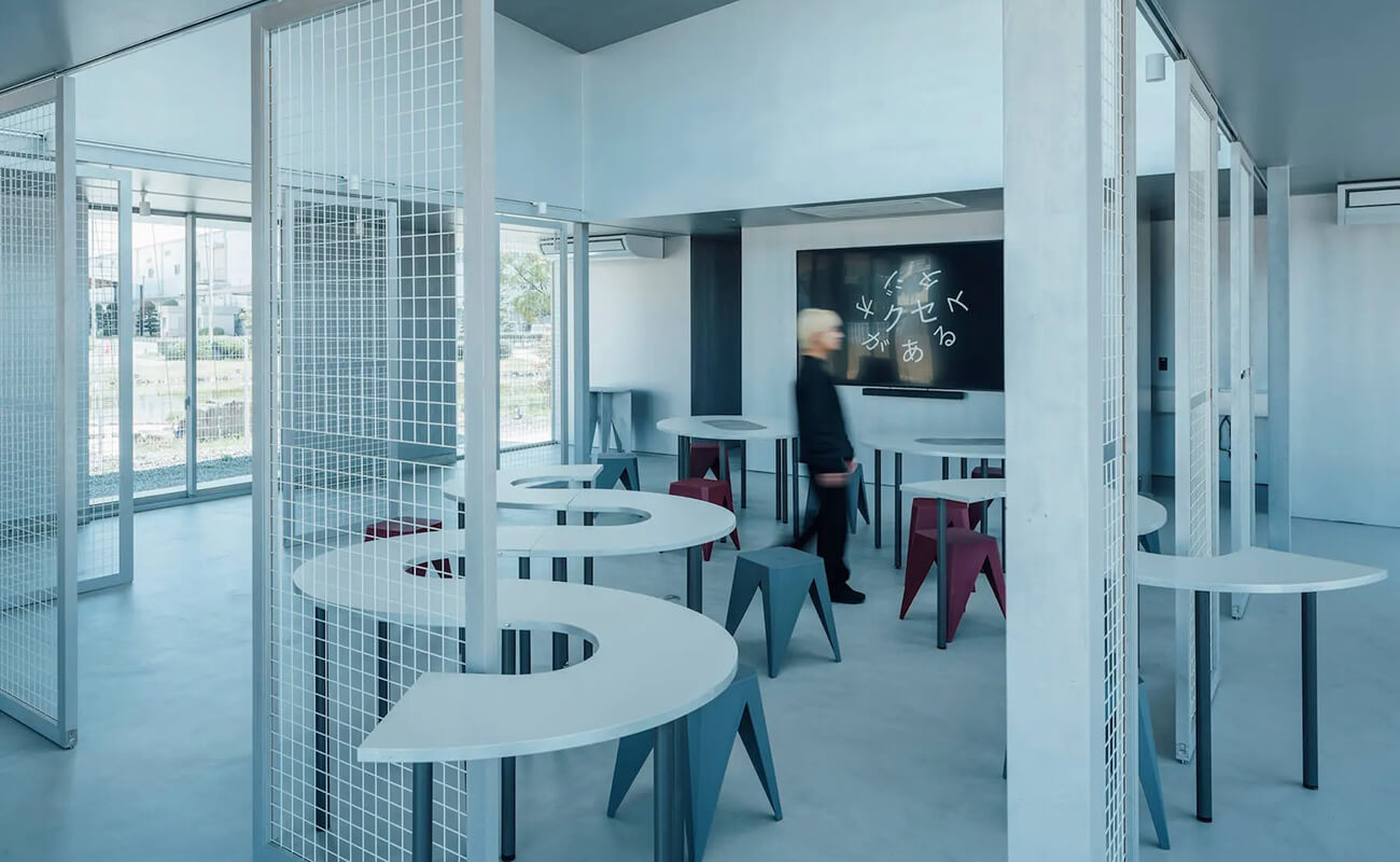 「クセがあるスタジオ」の室内風景。白い円弧状テーブルとカラフルなスツールが配置され、奥のモニターにロゴが表示されている。