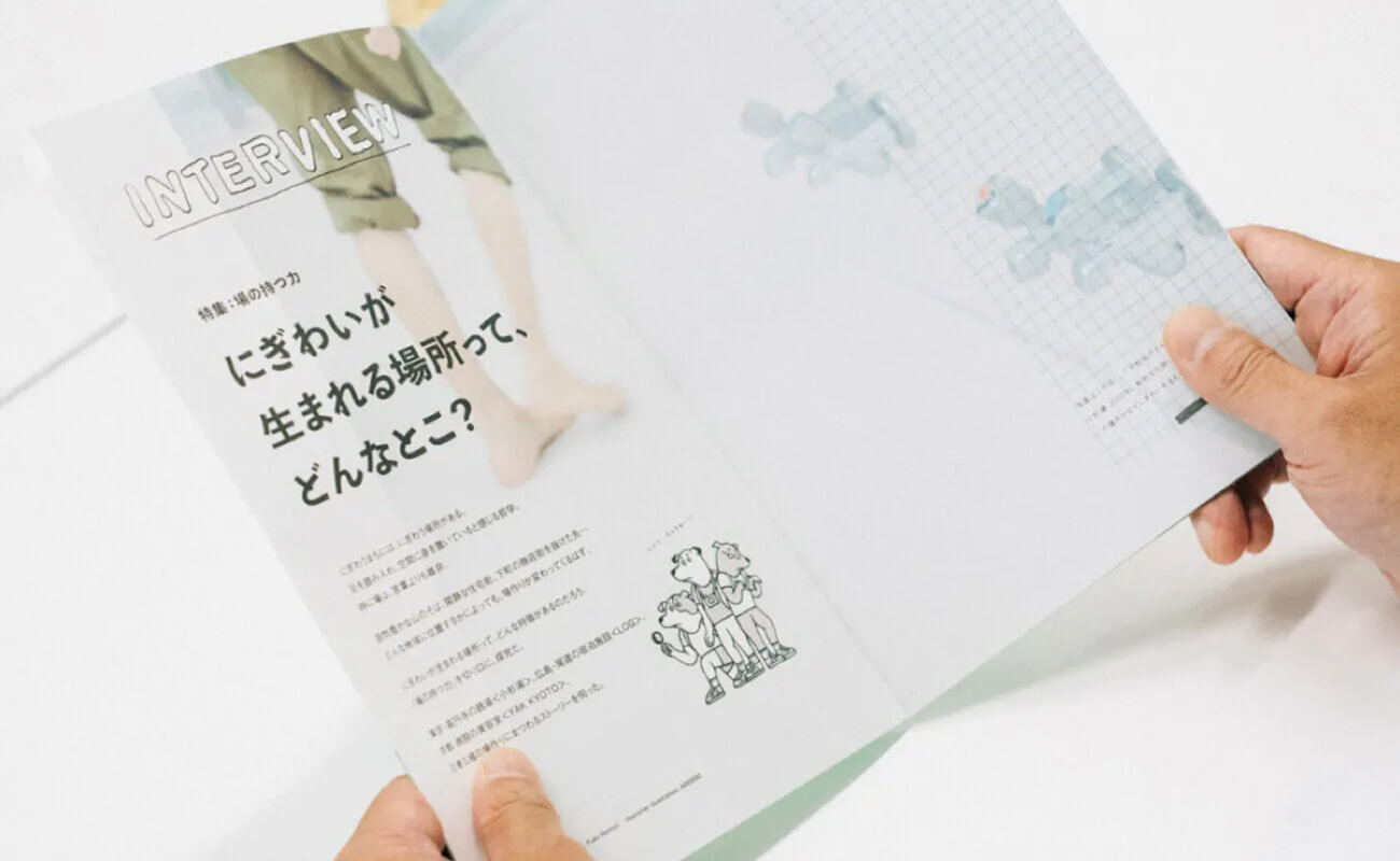 『アルケバボウ』を手に取って読む様子。誌面には「にぎわいが生まれる場所って、どんなとこ？」という特集タイトルが掲載されている。