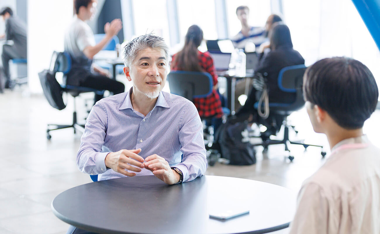 共創施設の一角で、諏訪光洋が聞き手と向き合いながら語っている様子