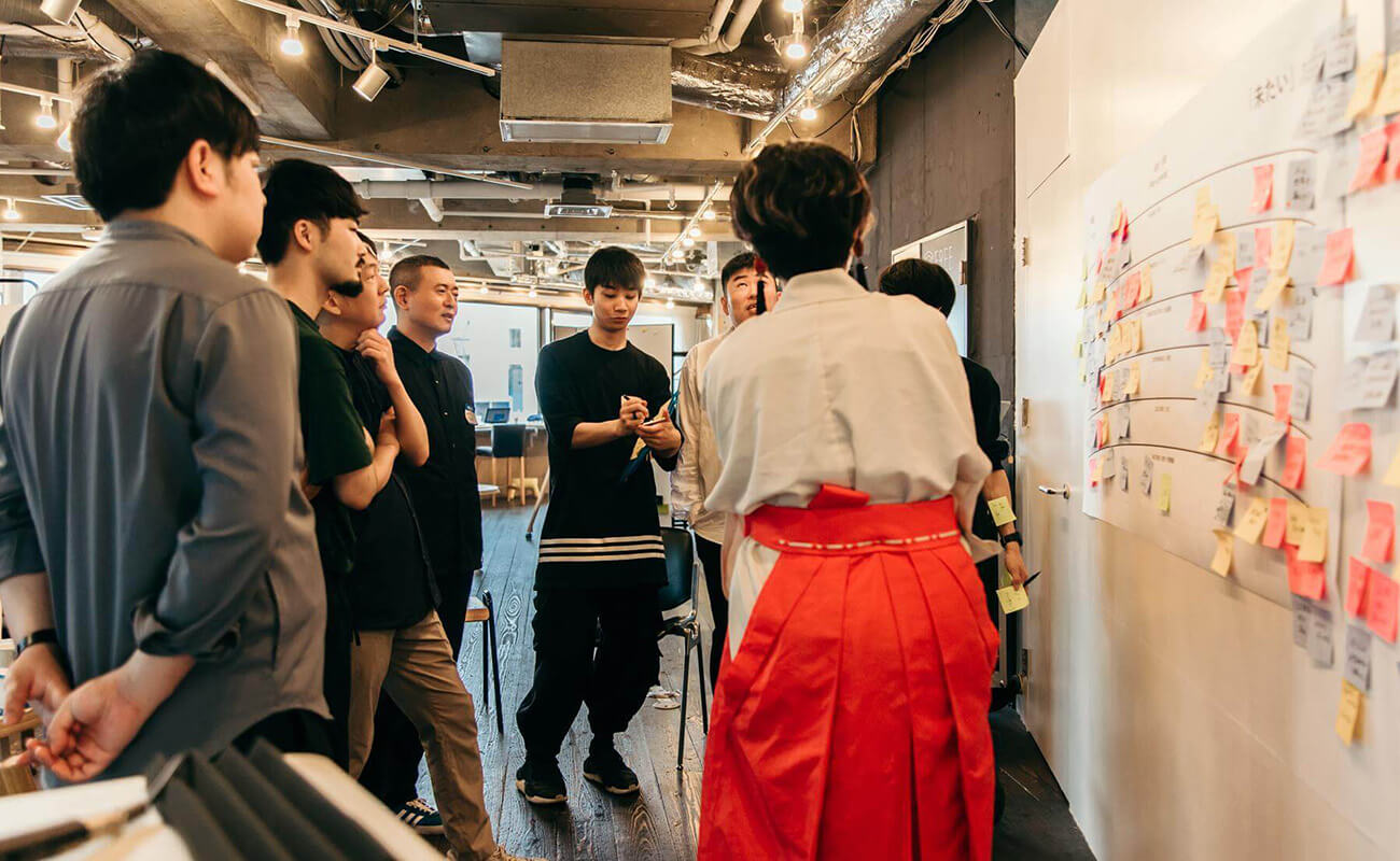 参加者が壁一面の付箋を前に、意見を出し合いながら議論している様子