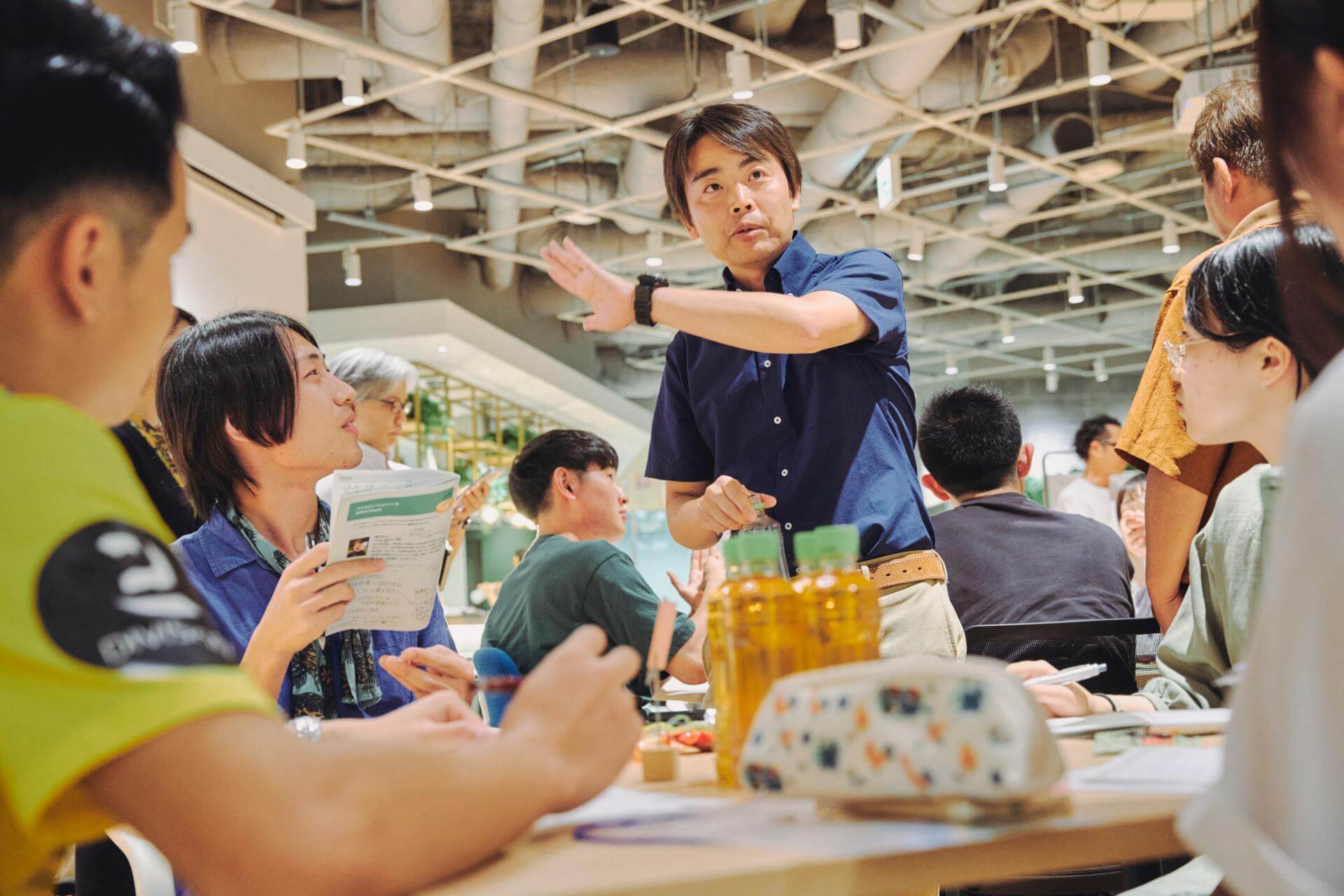 写真：学生たちの議論に混ざる深野祐也准教授