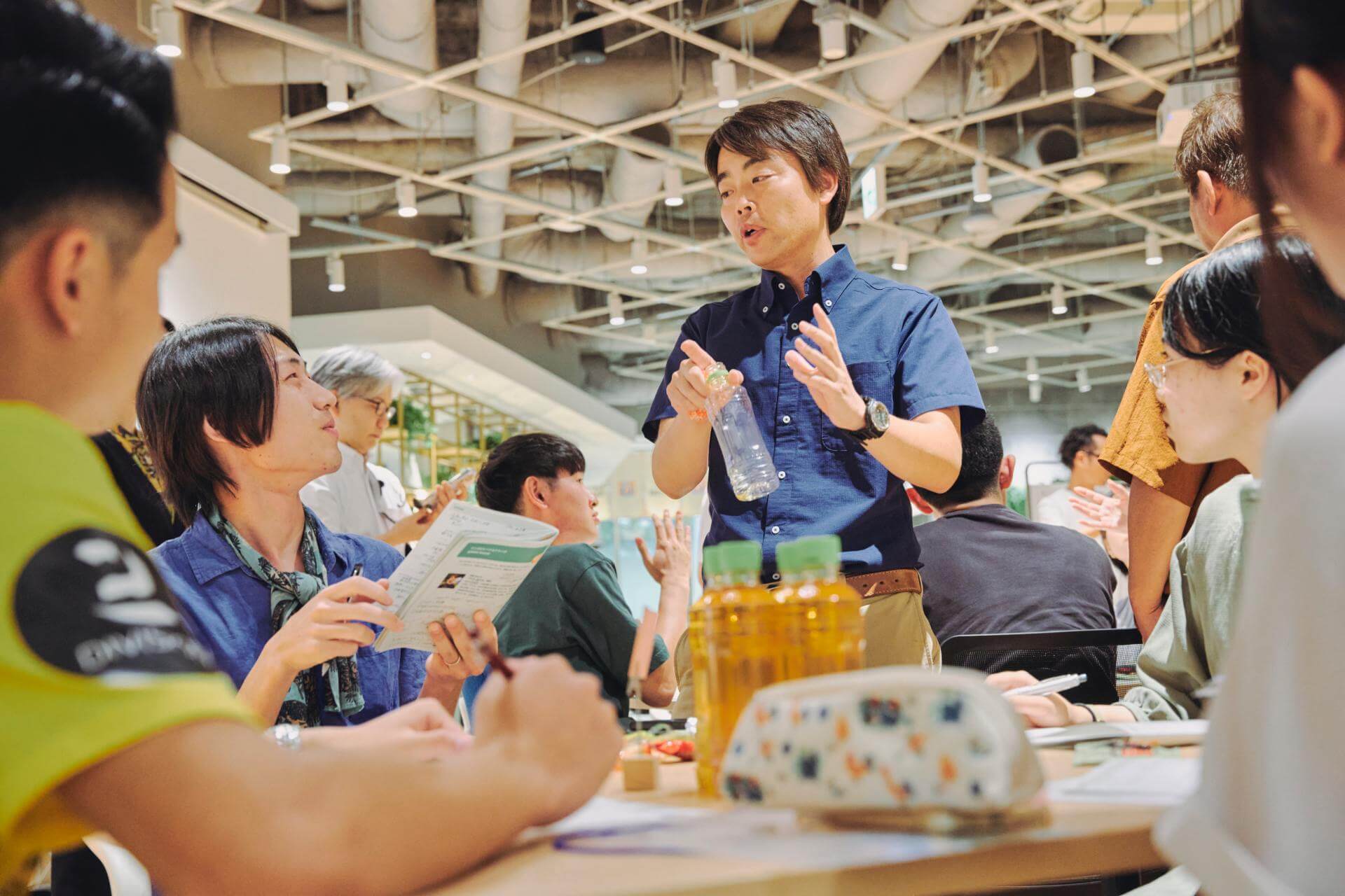 写真：学生たちの議論に混ざる深野祐也准教授