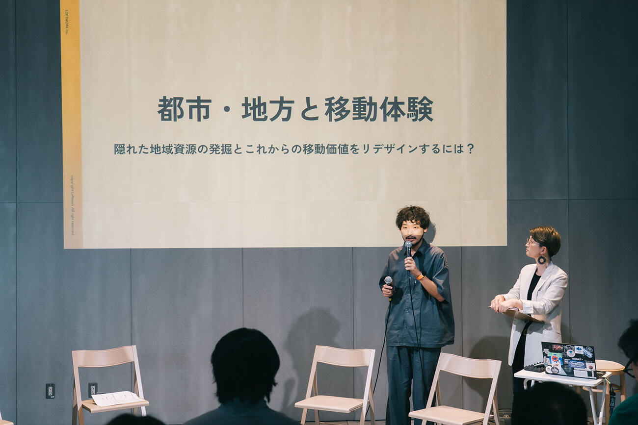 男性（茂谷さん）と女性（藤原）が登壇し、マイクを持って会場に対して語りかける様子。