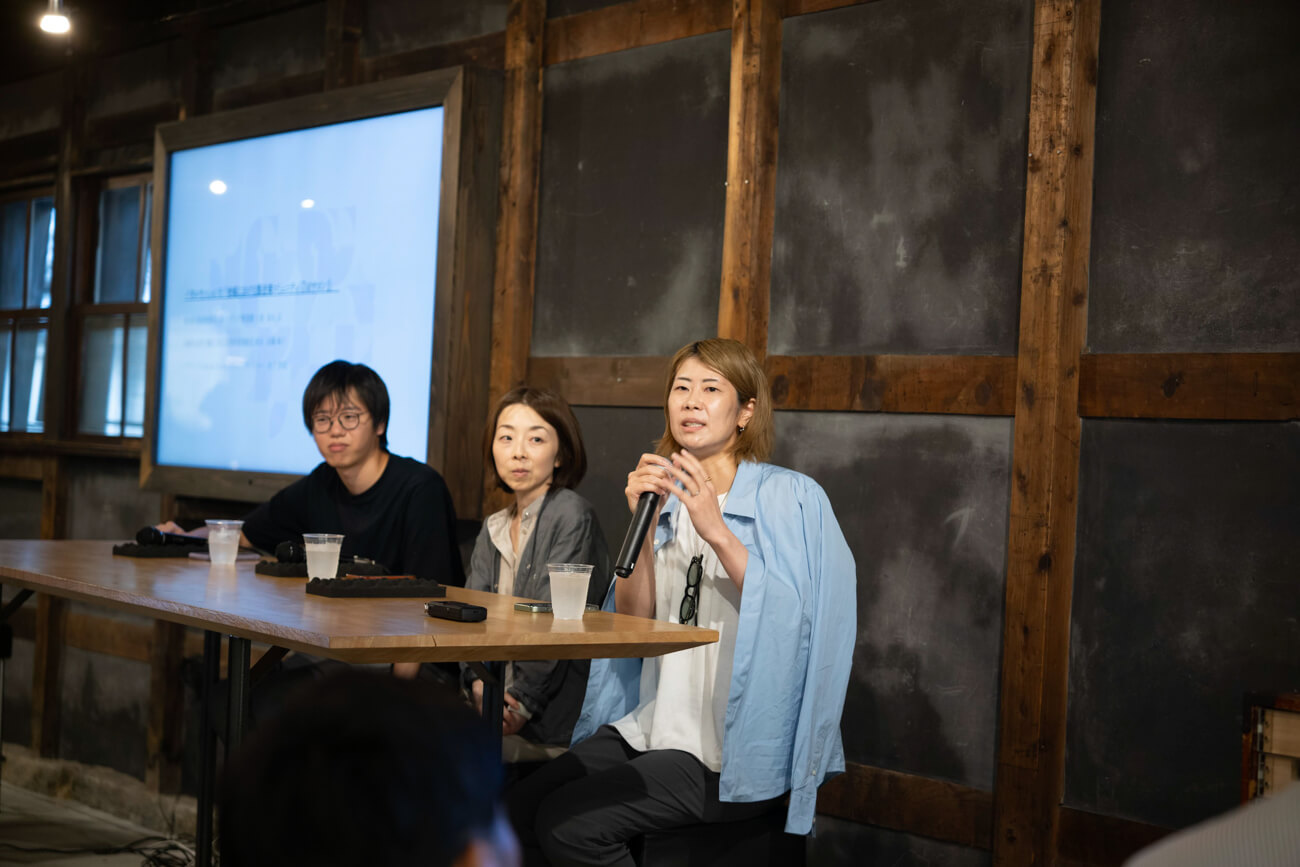 登壇者３名が観客の前で話している様子、横溝さんがマイクを握って話している