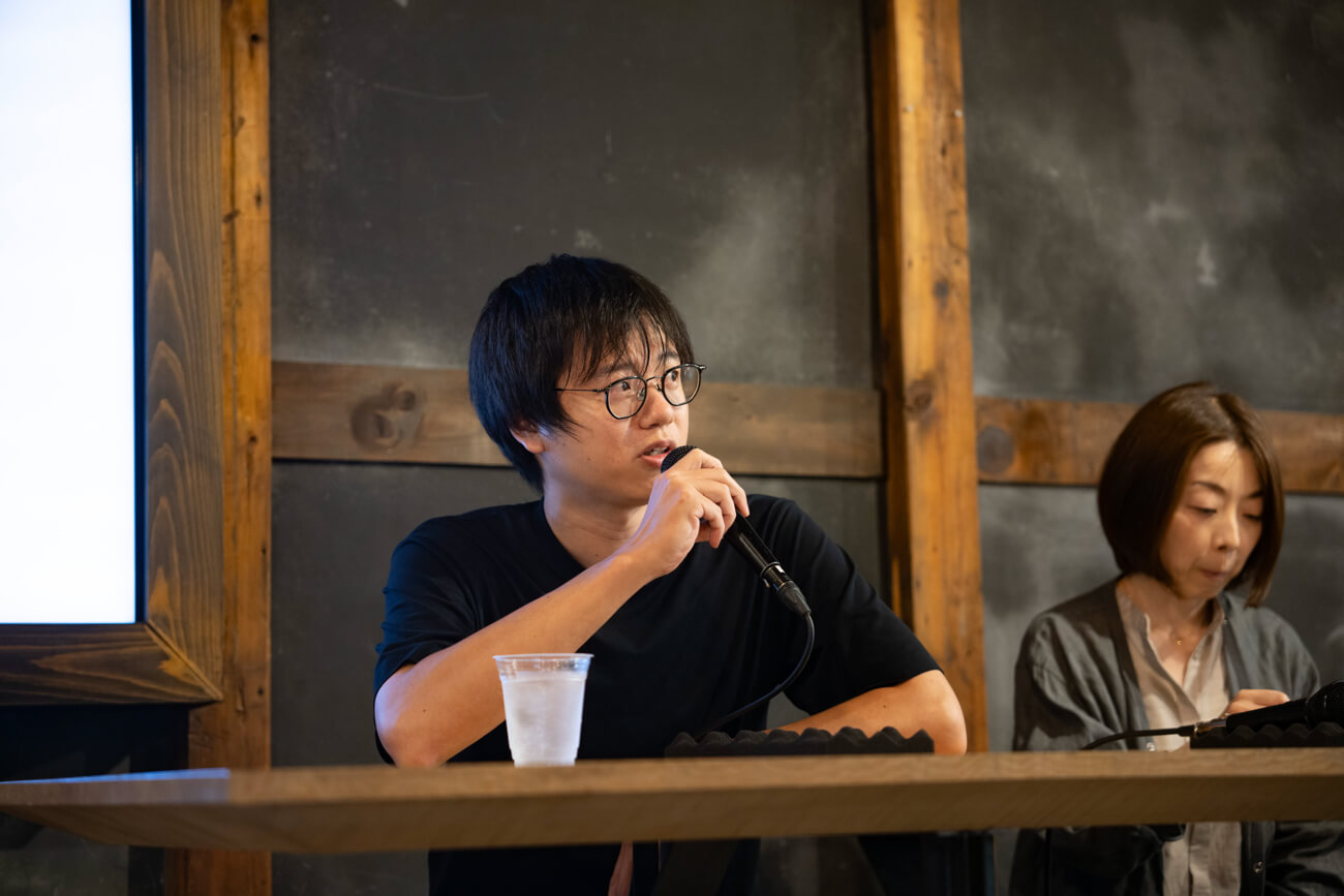 男性がマイクを持ち、観客に向けて話している様子