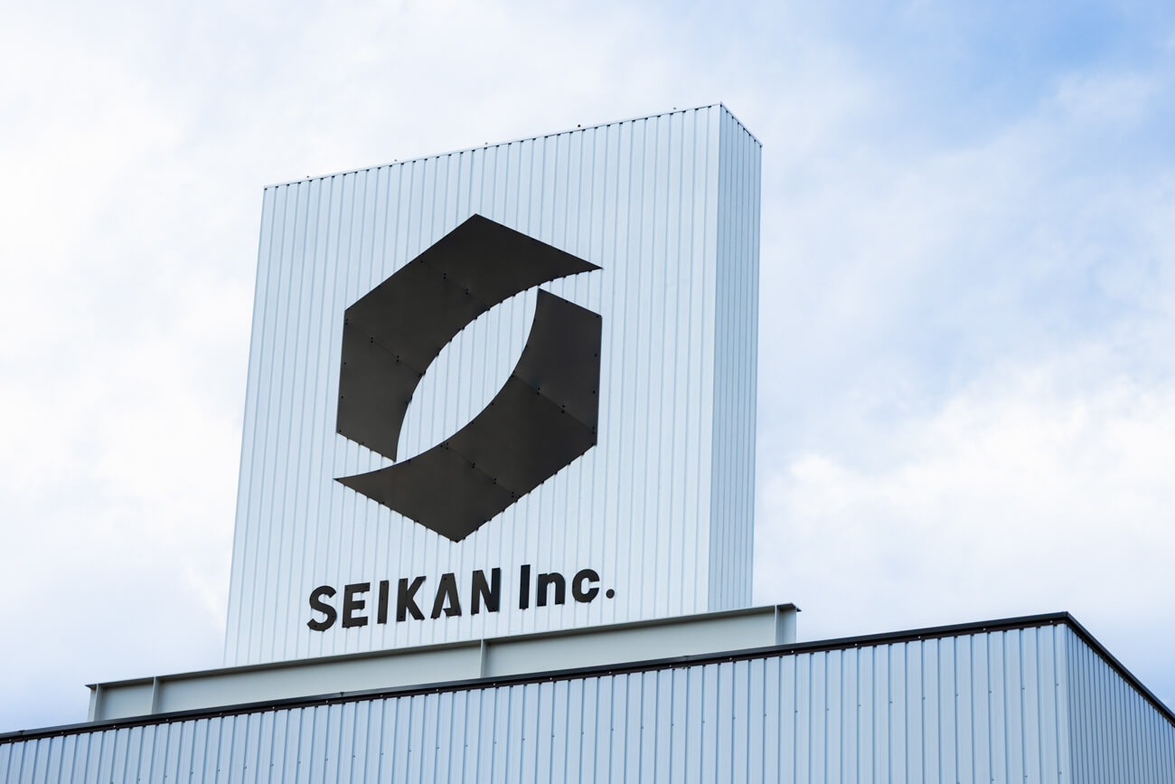 セイカン株式会社のロゴが掲げられた、会社の建物の一角の写真