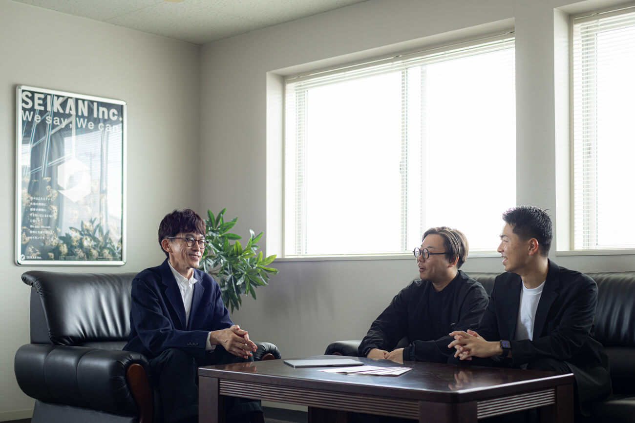 応接室で男性３名が席に着き、話をしている写真