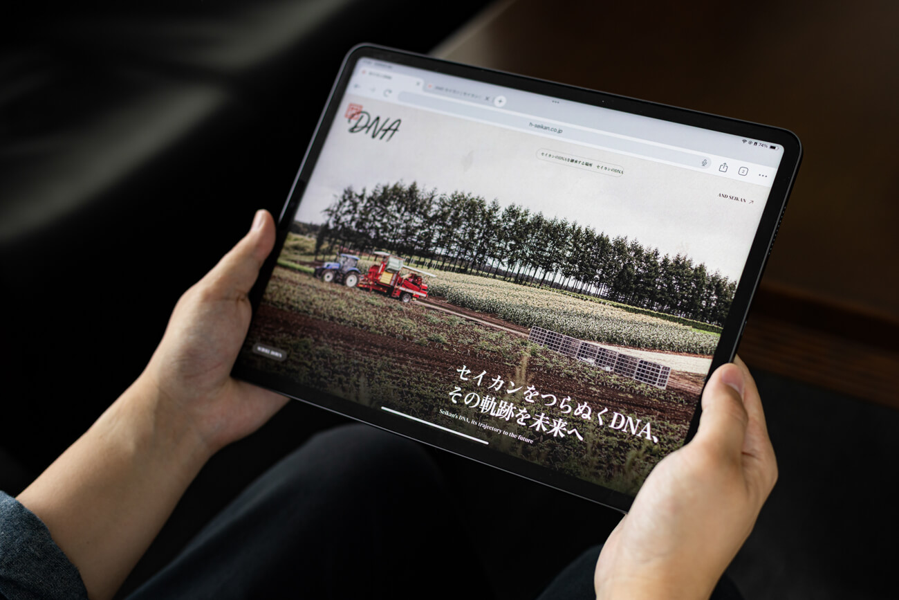 タブレットを持つ手元の写真。タブレットには、今回作られた社史のWEBサイトが表示されている