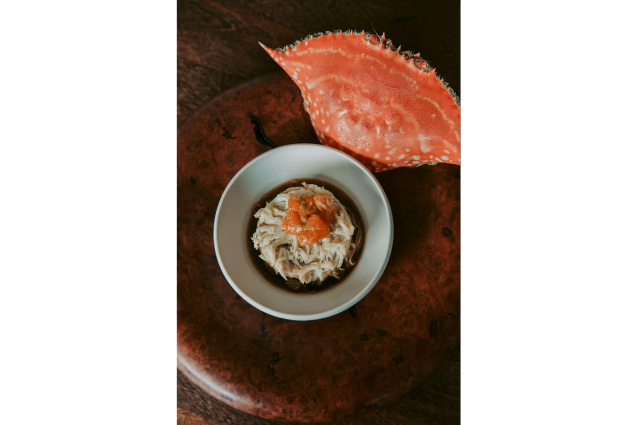 カニ料理の写真。うつわに盛られたカニのほぐし身のそばに、真っ赤な甲羅が添えられている