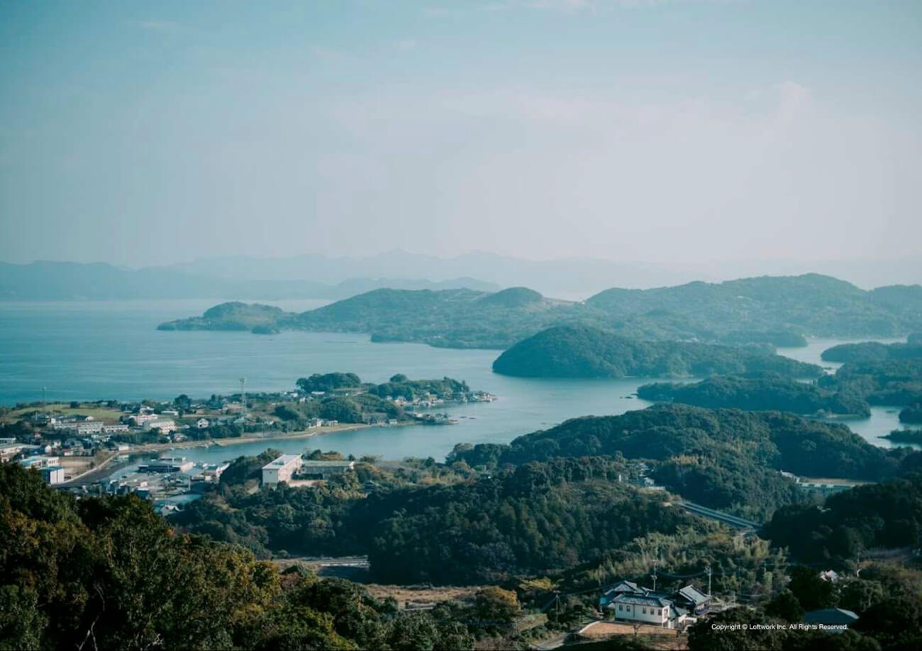 丘の上から海を望む写真。手前には自然豊かな山々が見える