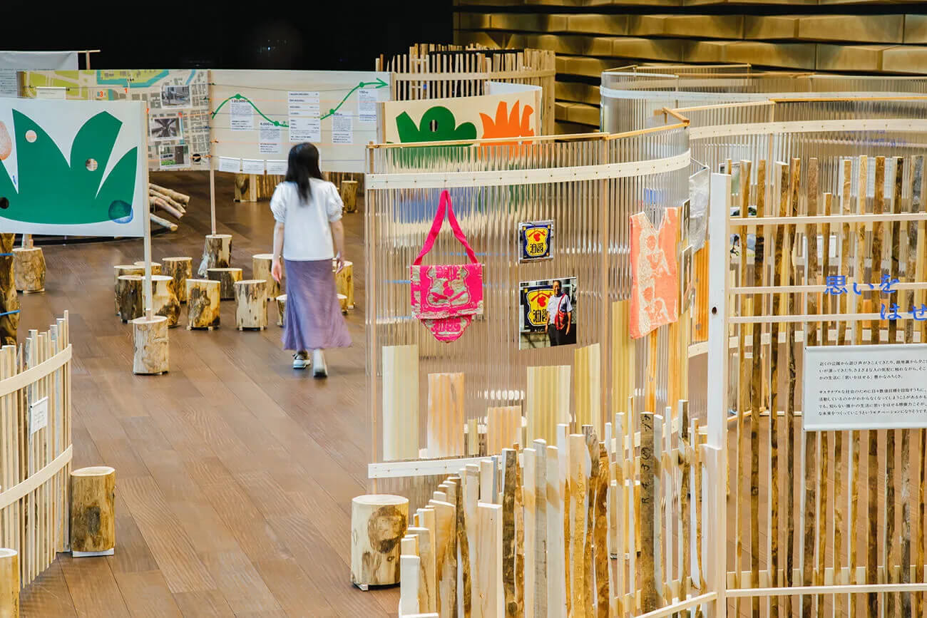 3周年記念展示『ちきゅうのみちくさ展』の様子。木材で作られた展示什器の間を参加者が歩いている様子