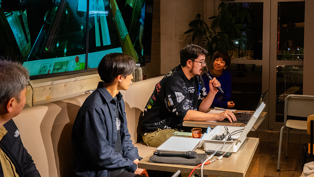 眼鏡を付けた大柄の男性が、金岡大輝。マイクを持って話をしている。