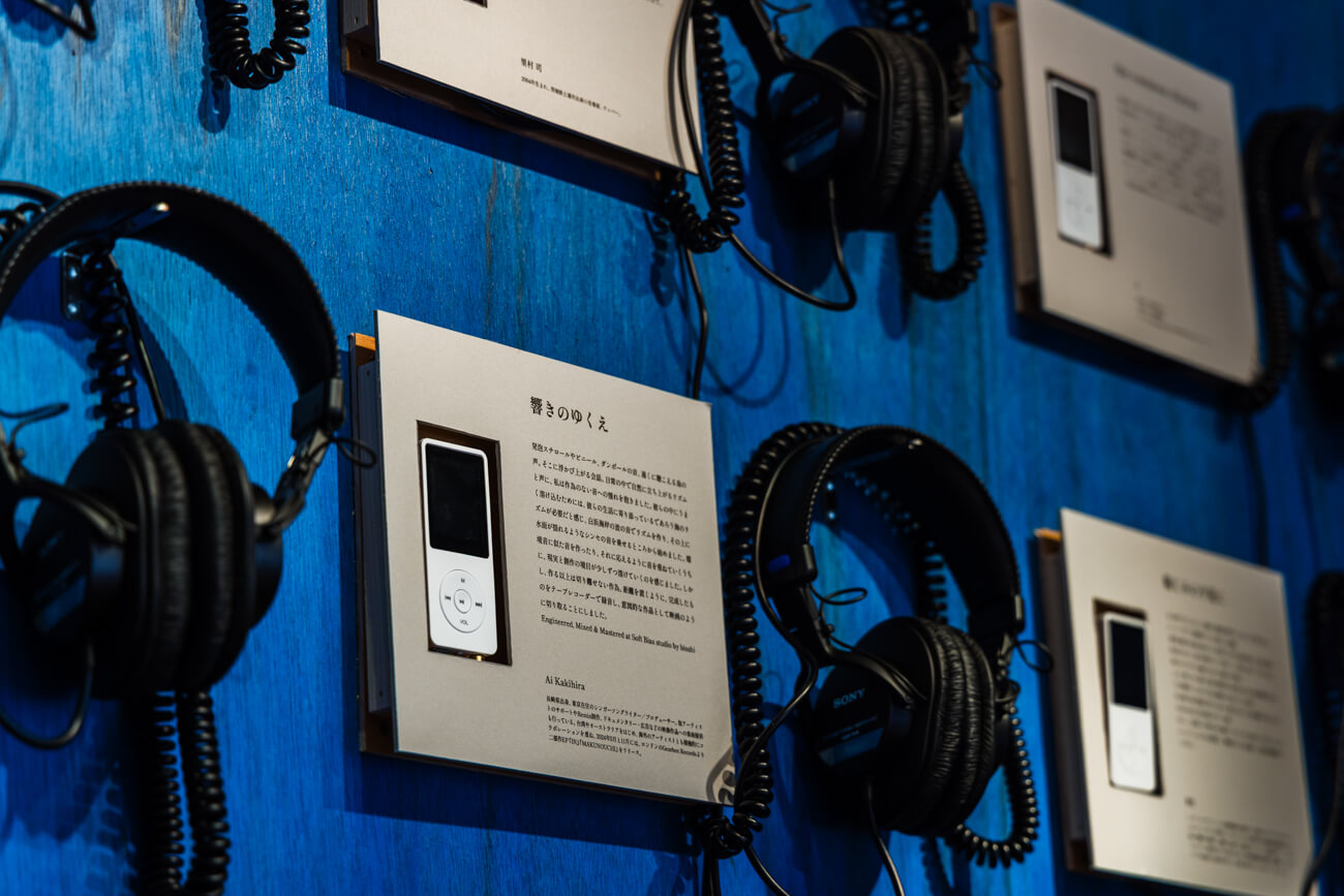 展示会場の様子。木の板に埋め込まれた音楽プレーヤーと、そこにつながるヘッドフォンがいくつも並ぶ