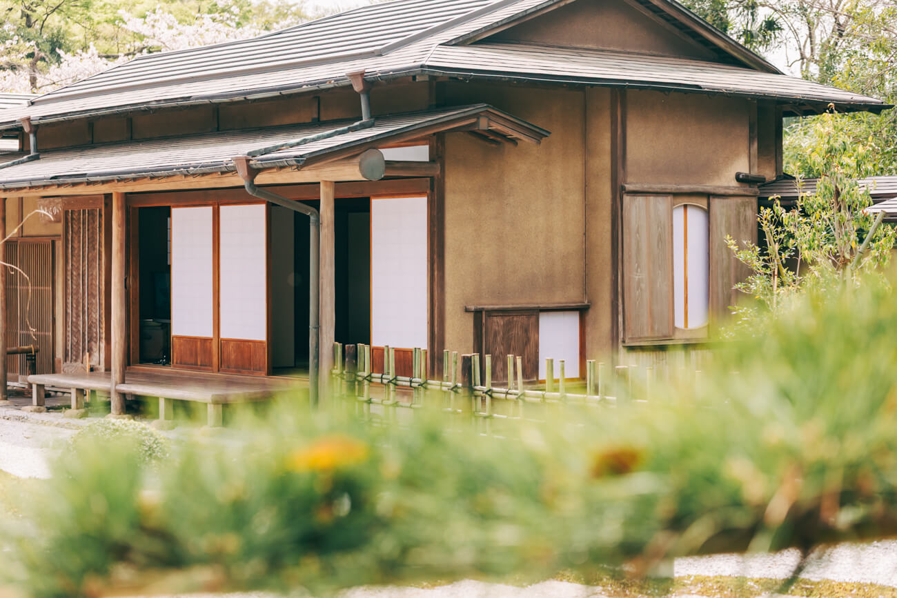 築40年の数寄屋仕立ての木造建築「いのはな亭」の写真。黒い瓦屋根と茶色の壁が印象的