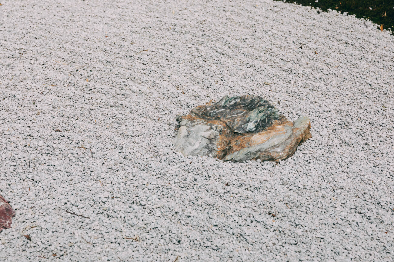 日本庭園の石組みにフォーカスした写真。庭園には砂と小石で砂紋が描かれている
