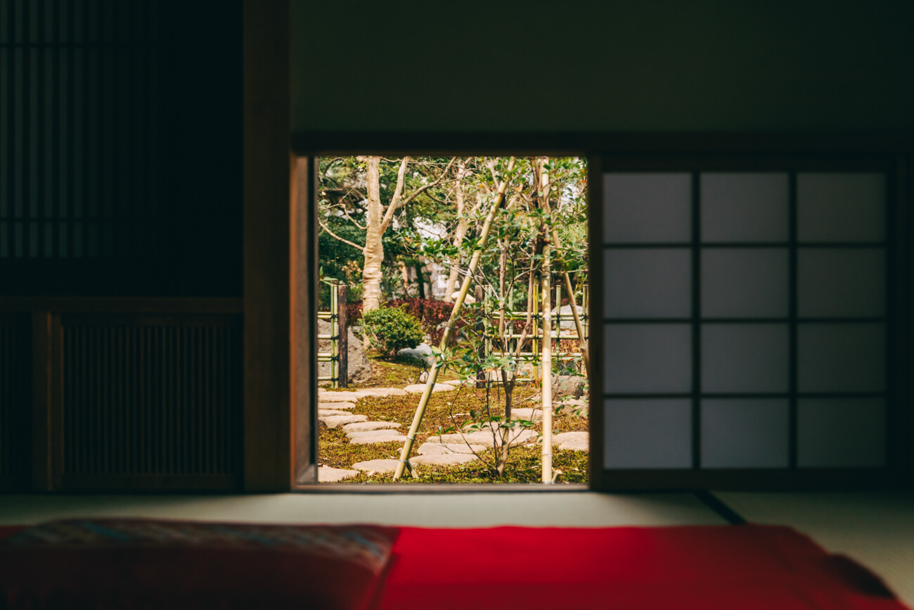 いのはな亭の中から、外の風景を見る目線の写真。開け放たれた障子の向こうに、庭園の木々が見える