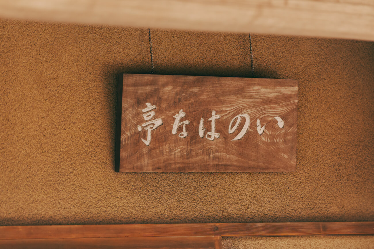 歴史を感じる「いのはな亭」の看板の写真。落ち着いた色の木の板に「いのはな亭」の文字が刻まれている