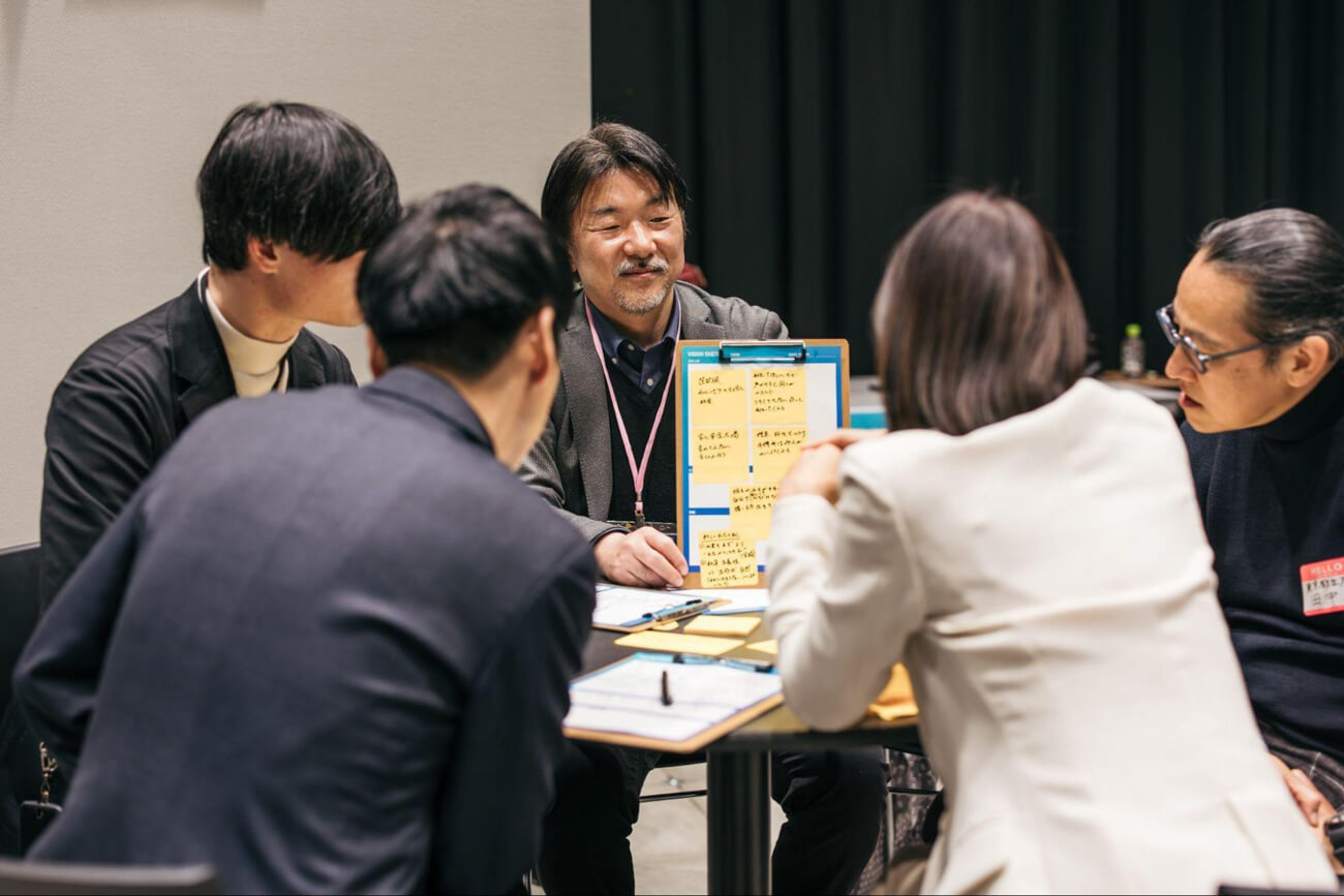 テーブルに向き合い、４〜５人一組でワークショップに取り組む人々の様子