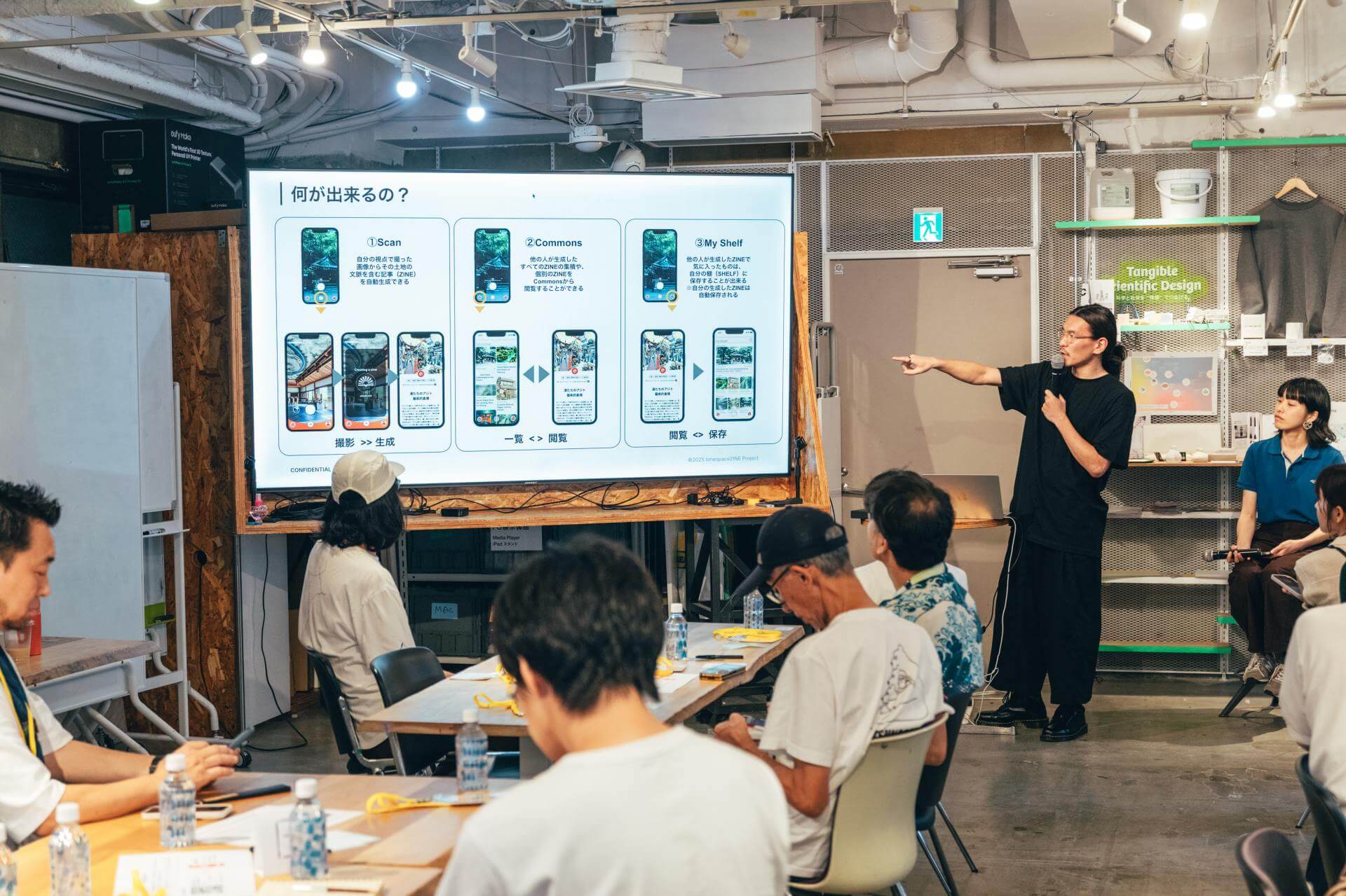 「何が出来るの？」と題したスライドを指しながら話す登壇者。スライドはtimespace ZINEの3つの機能を、画面遷移の図とともに示している。