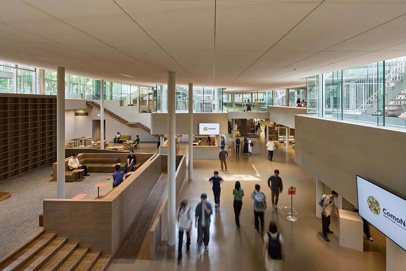 The central circulation area within the building. People move through the large atrium space, with lounges, staircases, and bookshelves arranged around it.