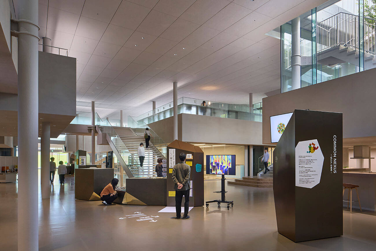 A scene from the special exhibition held inside the museum. Exhibits and videos are displayed on fixtures and monitors, with visitors stopping to view them.