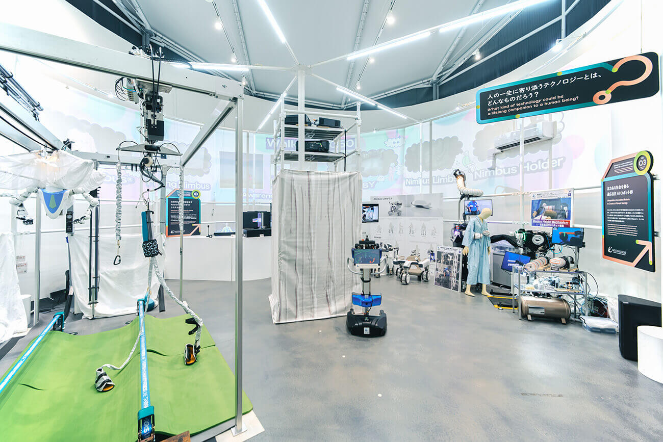 リハビリ支援機器や移動ロボットなど多様なロボット技術が並び、研究者向けの実験装置が組まれた無人の展示空間。未来の生活を支えるテクノロジーを紹介するブース全景。