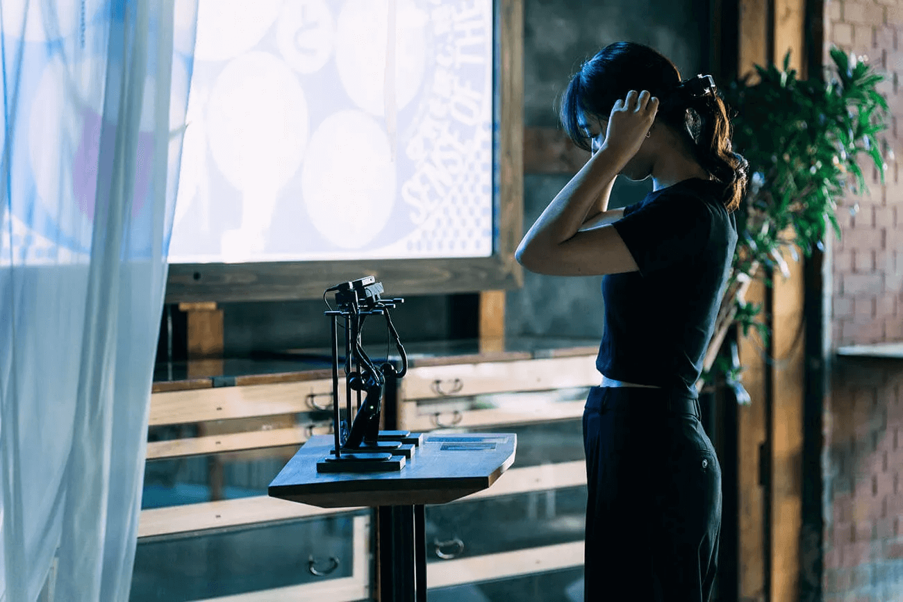 写真：佐野さん制作の作品の展示風景。女性が骨伝導デバイスを装着している