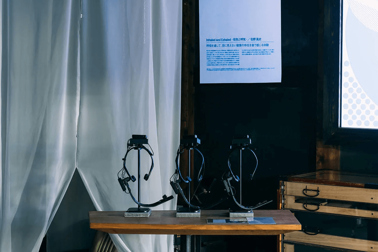 写真：佐野さんの制作した作品の展示デバイスを写した写真。頭に装着する骨伝導デバイスと、呼吸を計測・感知する場所は白いベールに包まれている
