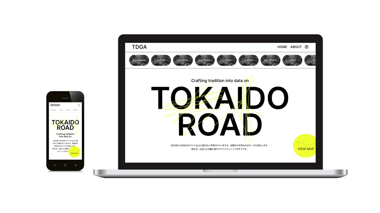 TGDA の Web プラットフォームのモックアップ。ノート PC とスマートフォンの画面に、白地に黒の大文字で「TOKAIDO ROAD」と表示されたトップページが映し出されている。