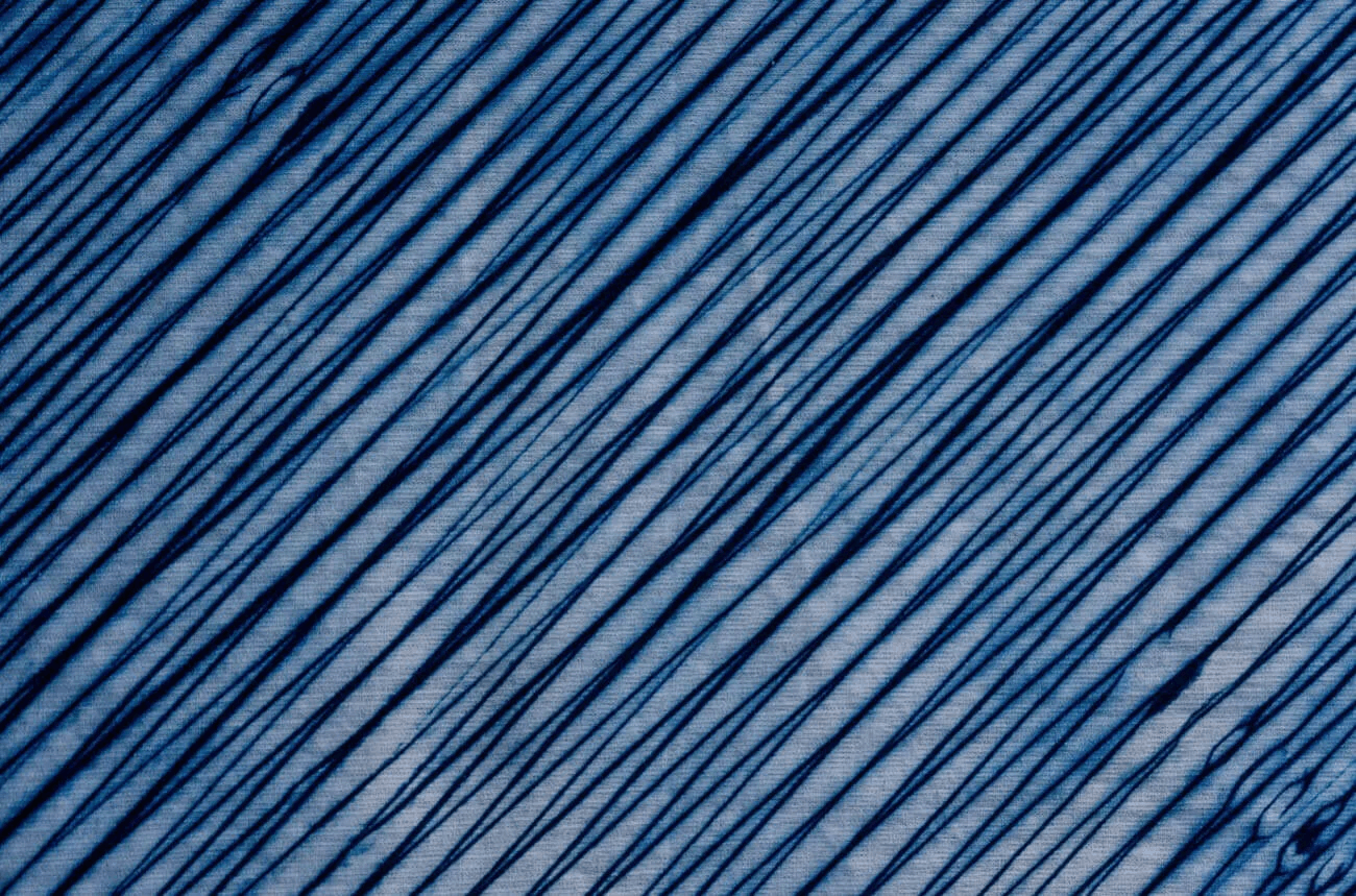 有松嵐絞りの布地のアップ写真。インディゴブルーストライプが無数に走り、力強いグラデーション模様が浮かび上がっている。