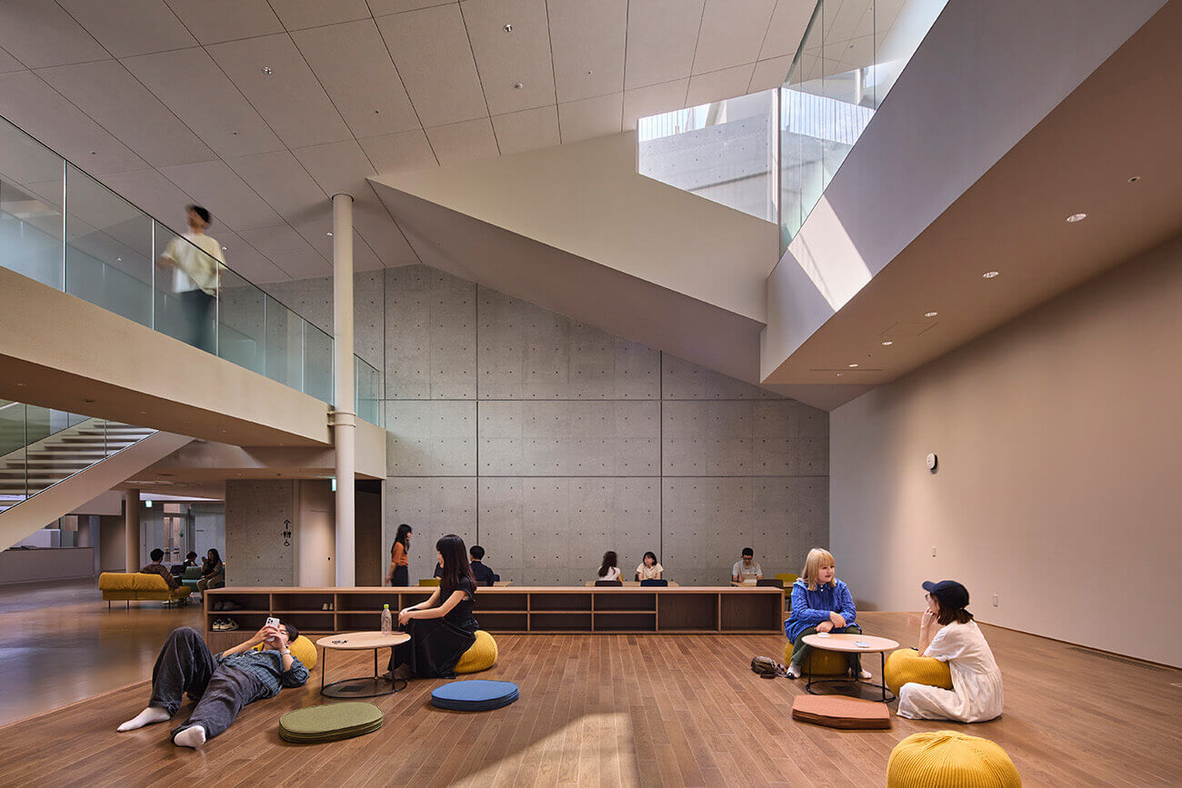 『ComoNe』施設内の様子。段差状の観覧席に人々が座り、奥にはカラフルな椅子が並ぶエリアや大きなスクリーンが設置されている。