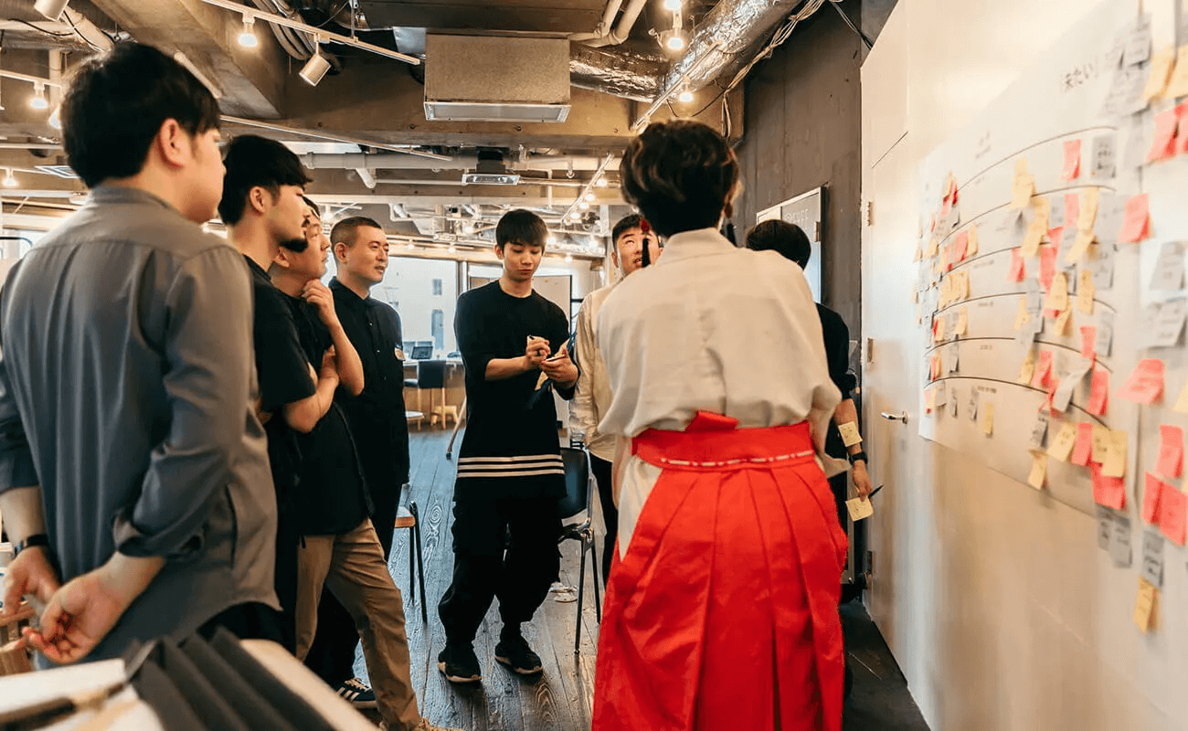 参加者が壁一面の付箋を前に、意見を出し合いながら議論している様子