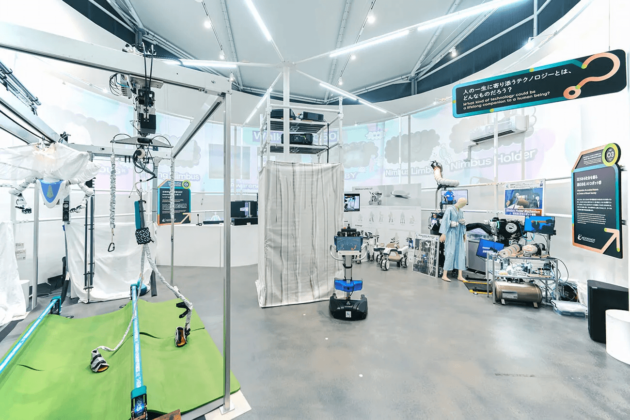 リハビリ支援機器や移動ロボットなど多様なロボット技術が並び、研究者向けの実験装置が組まれた無人の展示空間。未来の生活を支えるテクノロジーを紹介するブース全景。